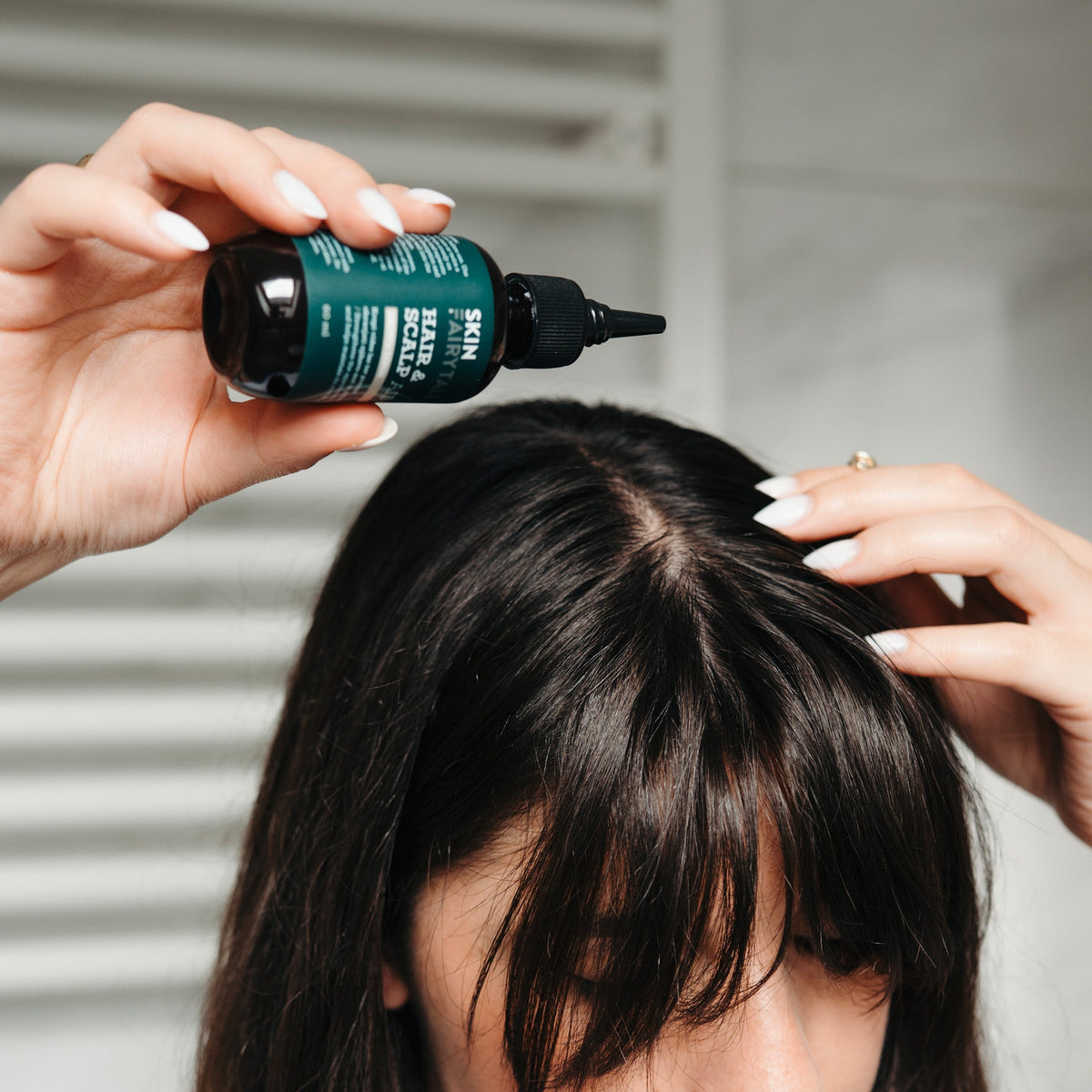 A woman applying the serum to her scalp